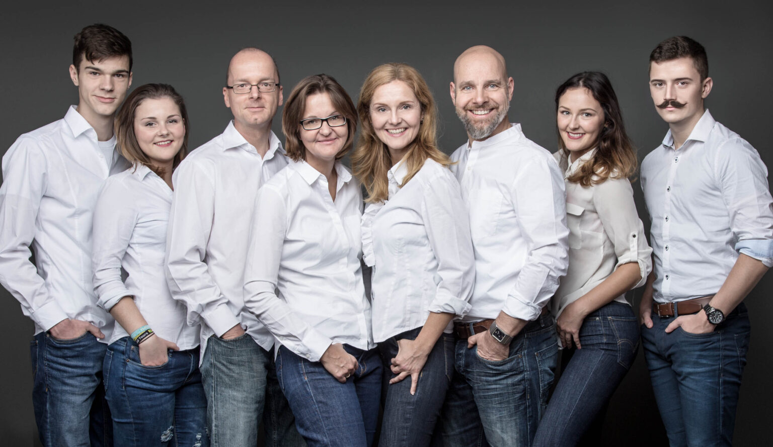 Familienfoto in Jeans und weißen Hemden von zwei Familien. Die Eltern mit Ihren erwachsenen Töchtern und Söhnen bei einem Familienfotos-Shooting in Berlin